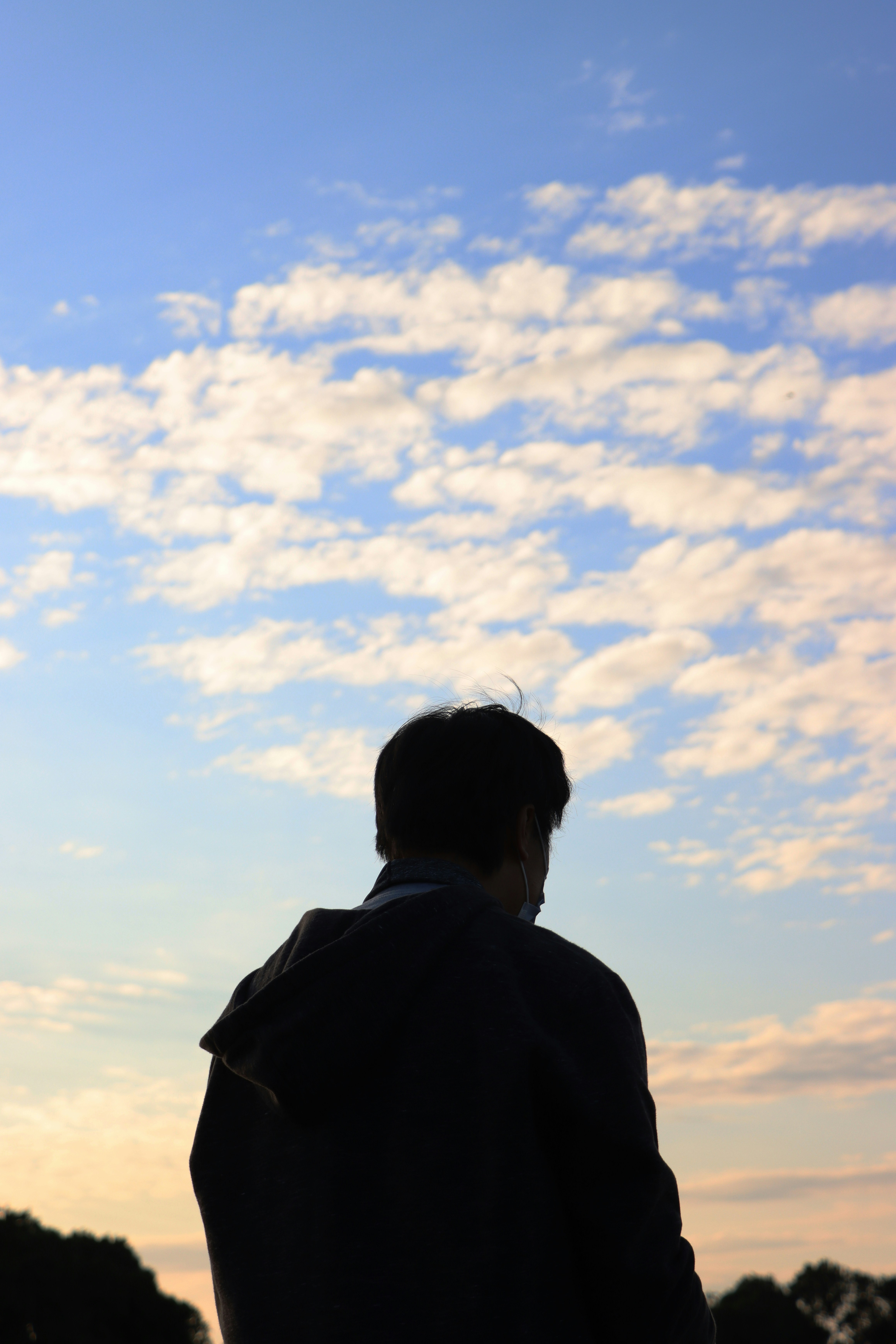 a man standing in front of a cloudy sky