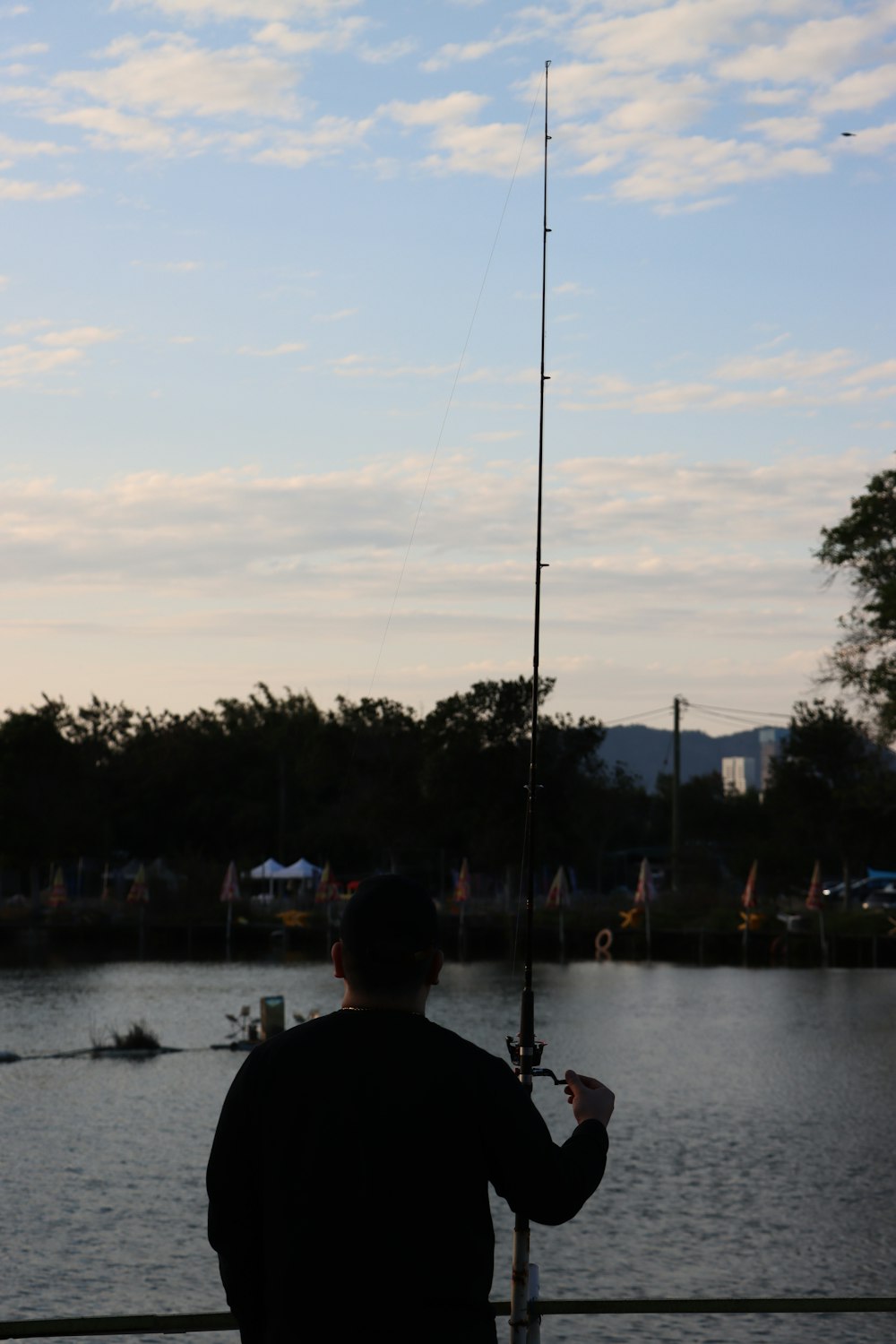 a man standing on a pier holding a fishing pole
