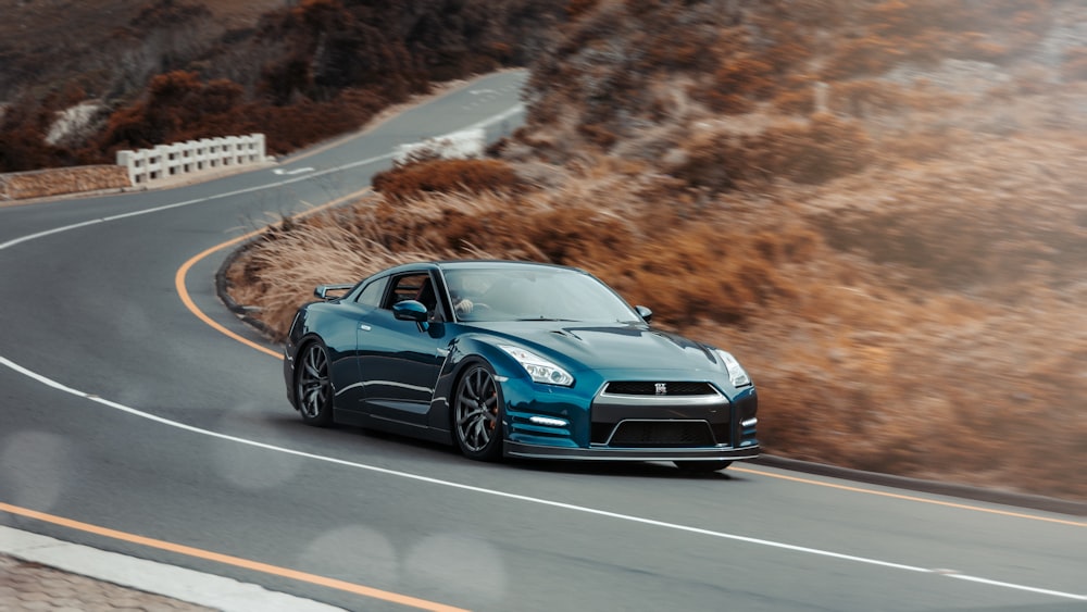 a blue sports car driving down a winding road