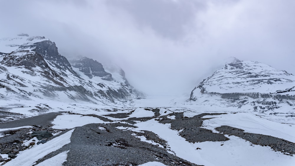 a snow covered mountain range with a cloudy sky