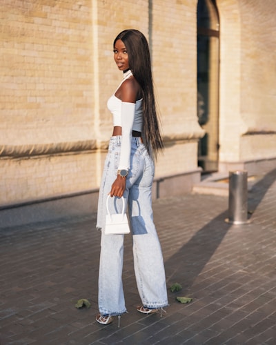 a woman with long hair standing on a sidewalk