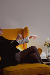 a woman sitting on a yellow chair pointing at something