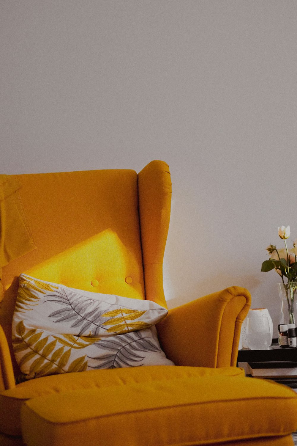 a living room with a yellow chair and a vase of flowers