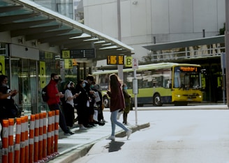 a group of people standing on a sidewalk next to a bus