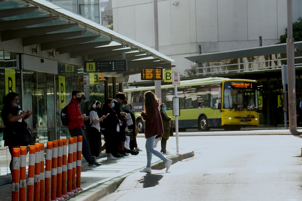 a group of people standing on a sidewalk next to a bus