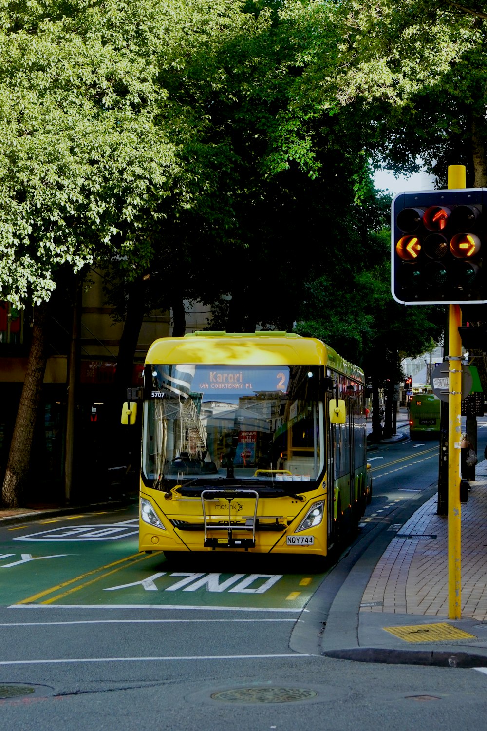 a yellow bus driving down a street next to a traffic light