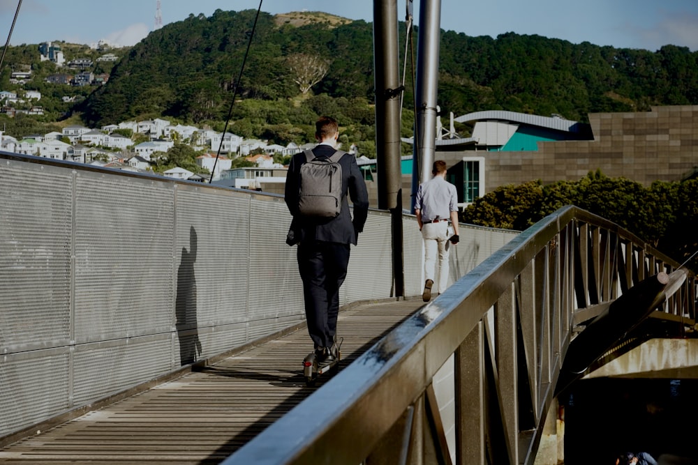 a man with a backpack walks across a bridge