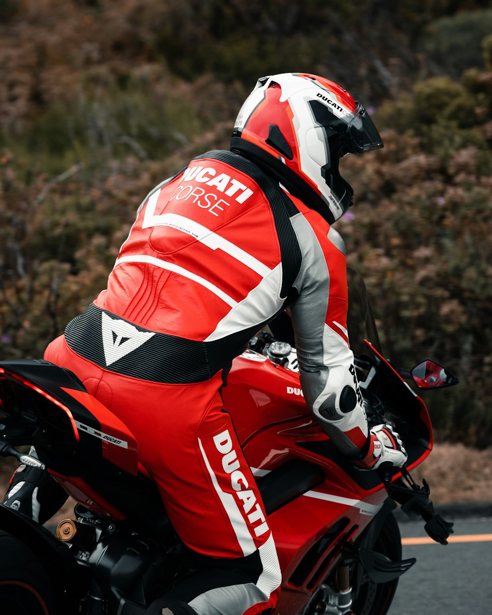 a man riding a red motorcycle down a street