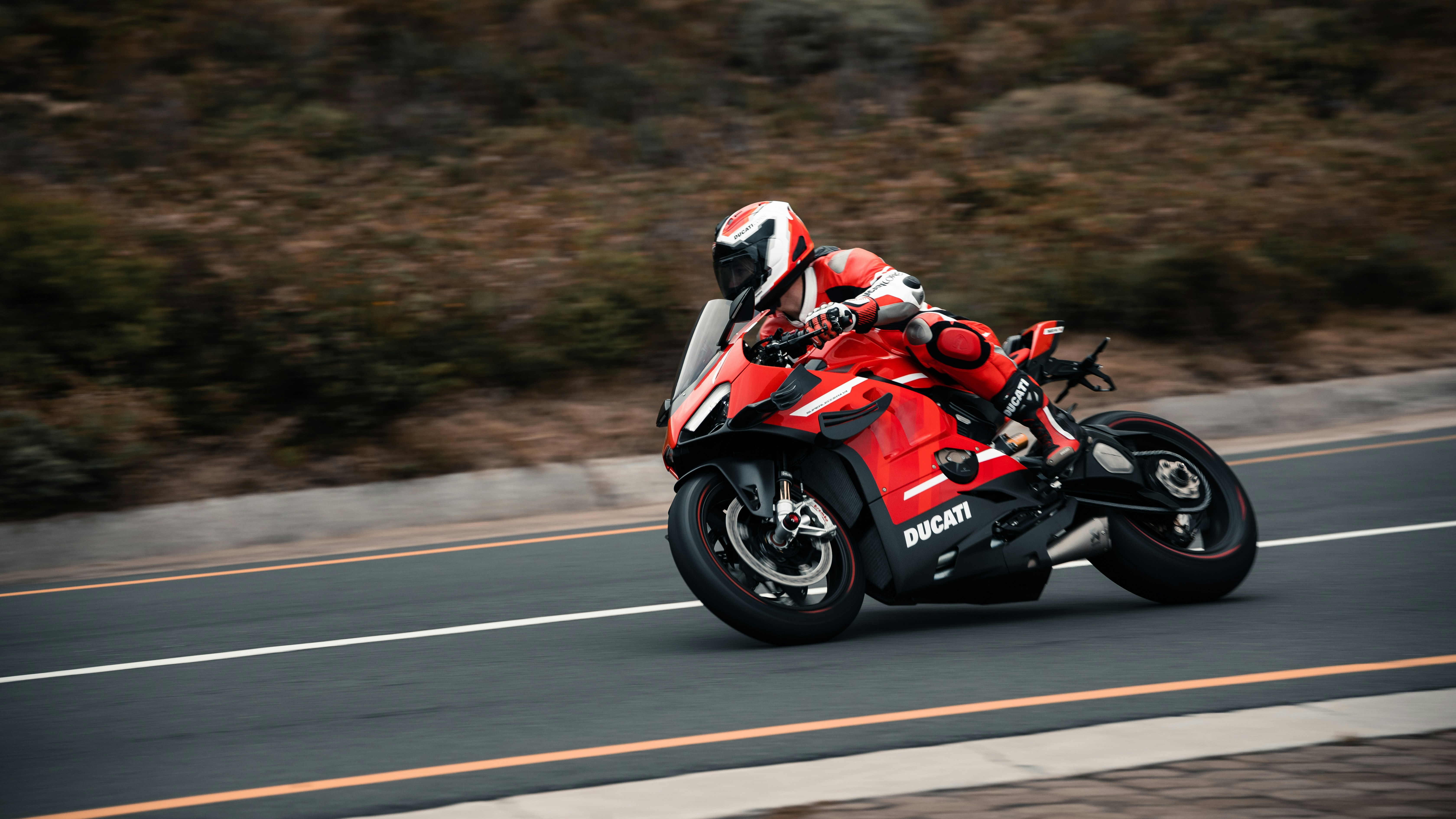 a man riding a red motorcycle down a curvy road