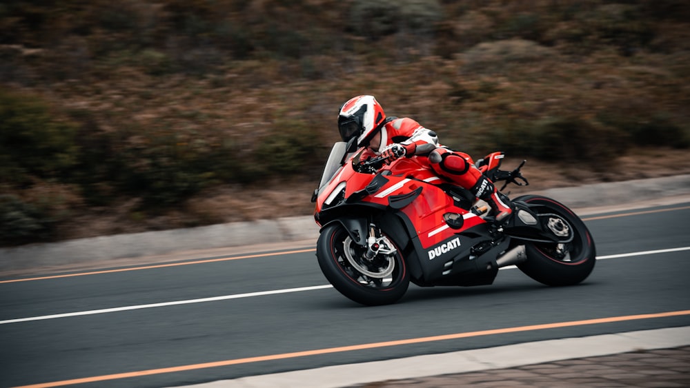 Un hombre conduciendo una motocicleta roja por una carretera con curvas
