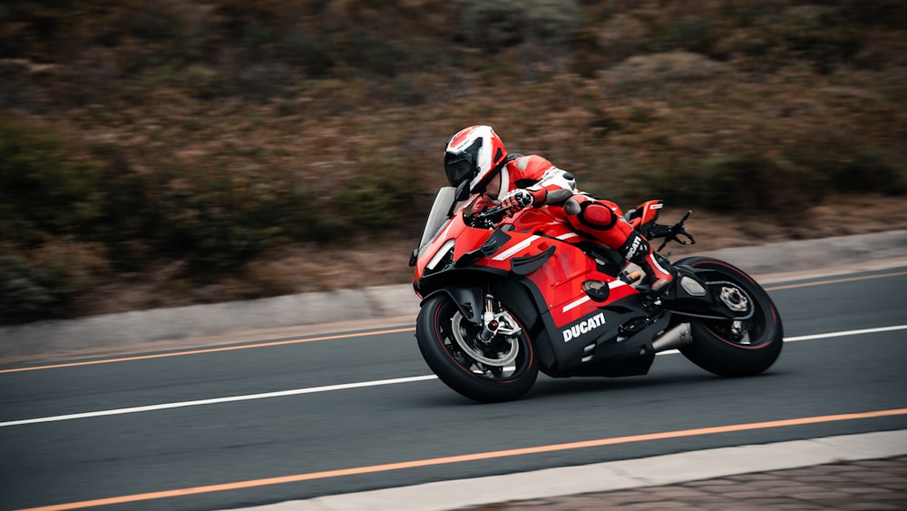 a man riding a red motorcycle down a curvy road