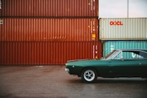 a green car parked in front of a shipping container