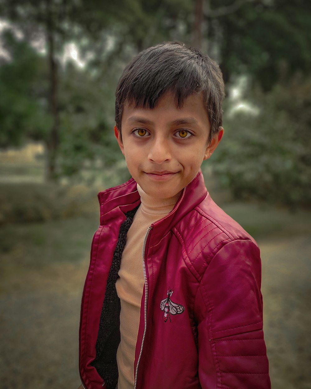 a young boy wearing a red jacket and smiling