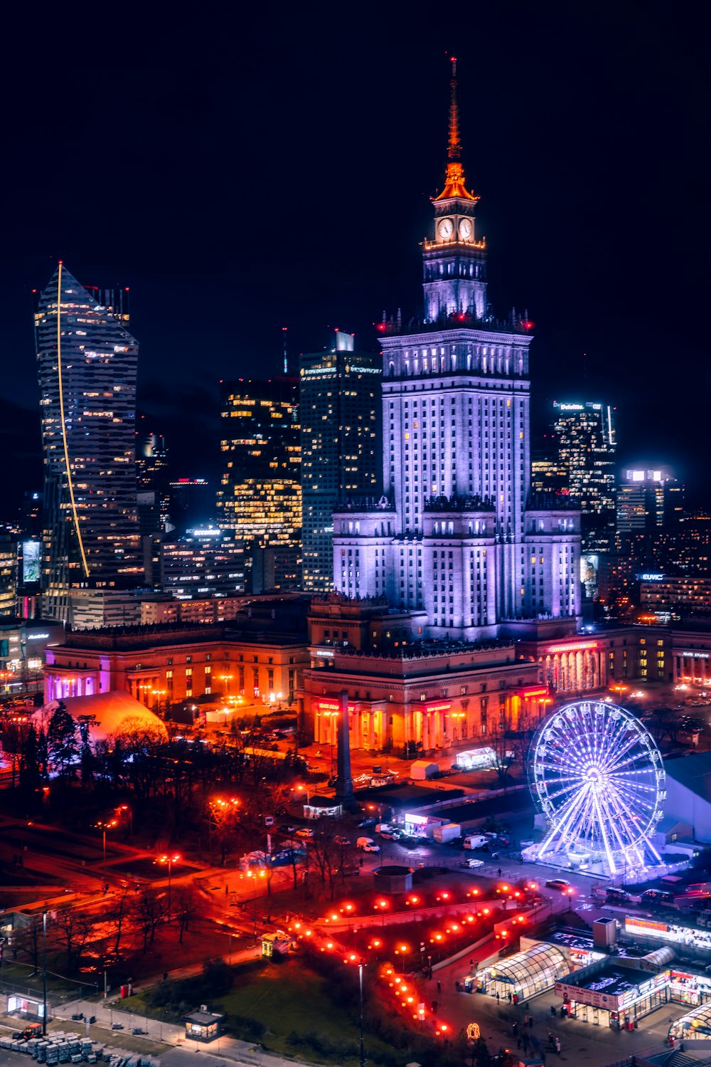 a city skyline at night with a ferris wheel in the foreground