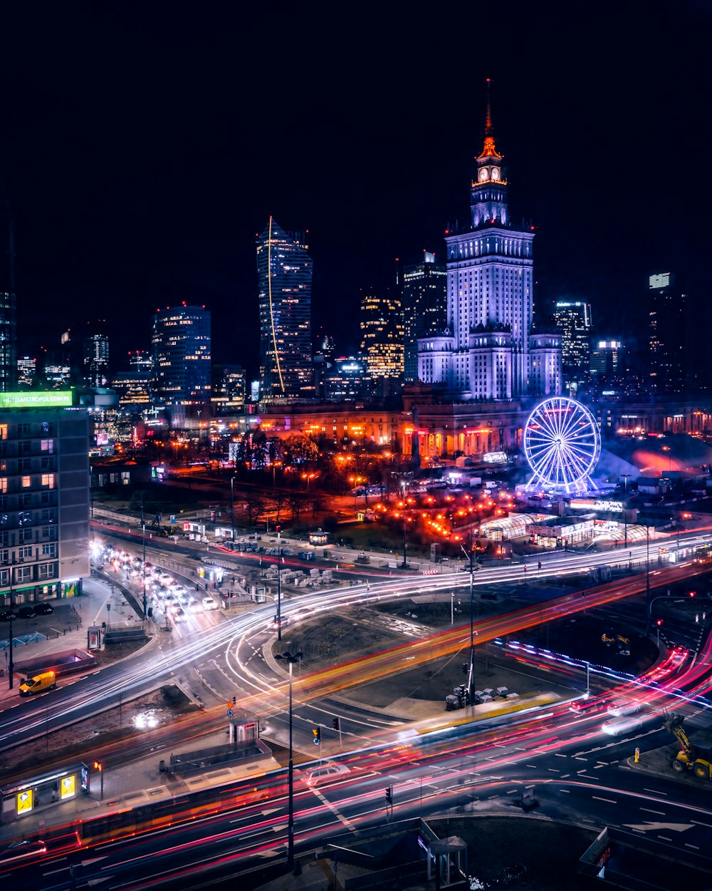 a city at night with a ferris wheel in the background