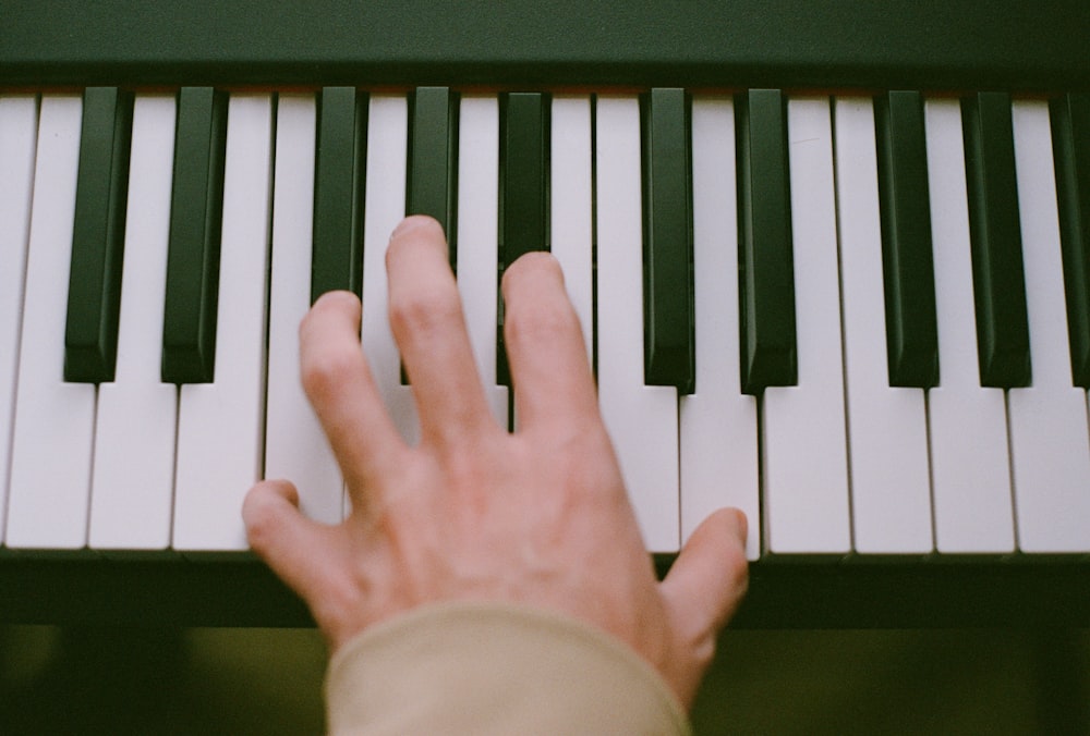 a person's hand on a piano keyboard