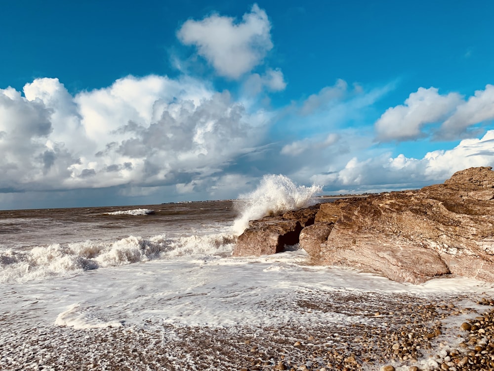 a large wave crashing into a rocky shore