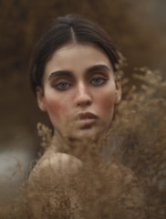 Portrait of Cristiane in a natural setting with soft earth tones and organic textures.
