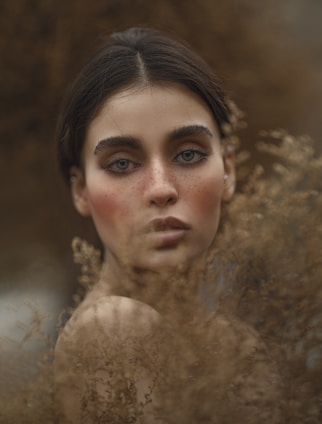 Portrait of Cristiane in a natural setting with soft earth tones and organic textures.