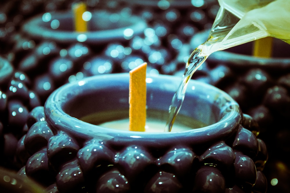 a person pouring liquid into a blue bowl