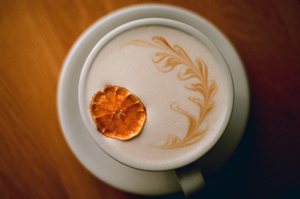 a cup of coffee with a piece of orange on top of it
