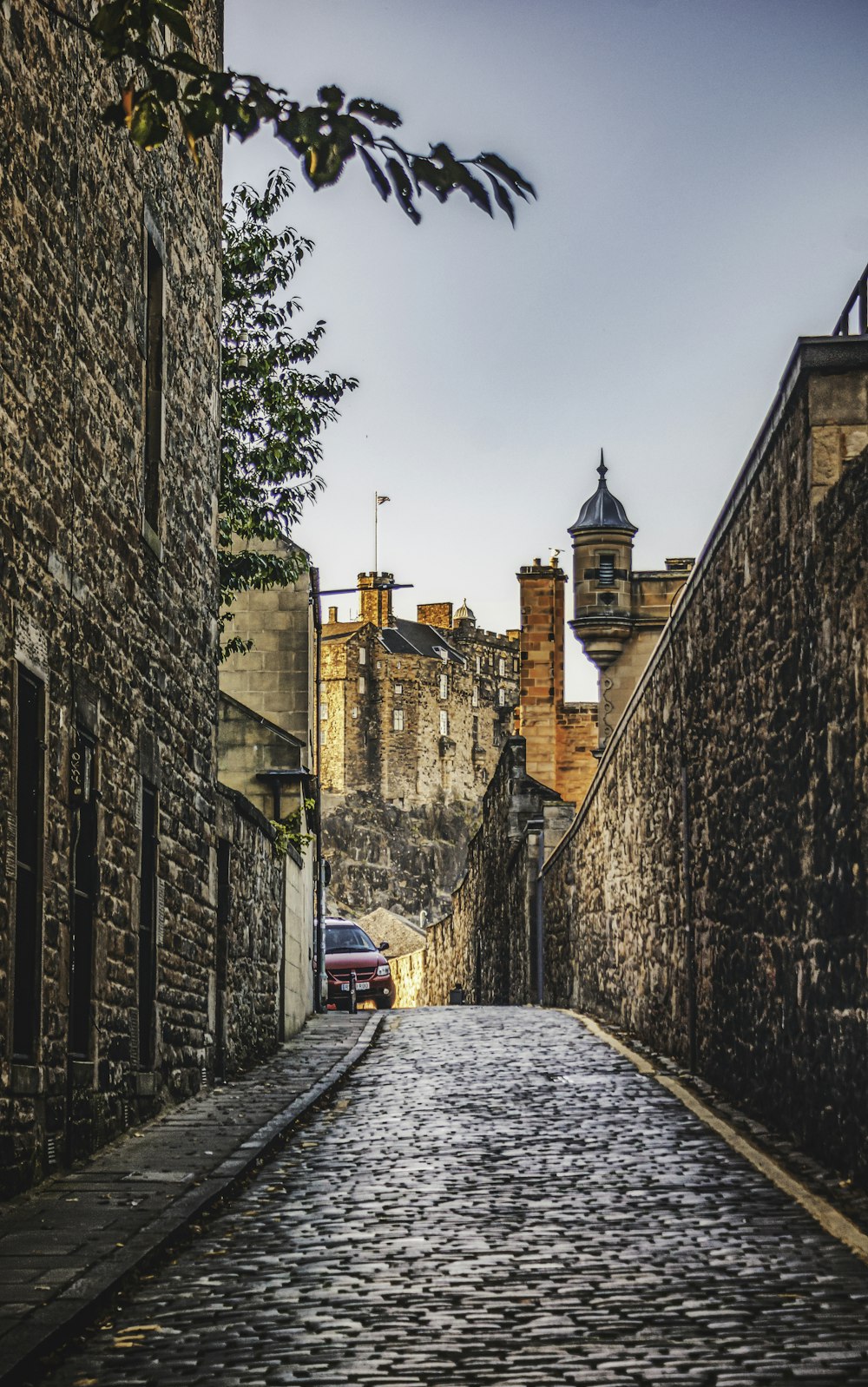 a cobblestone street with a car parked on the side