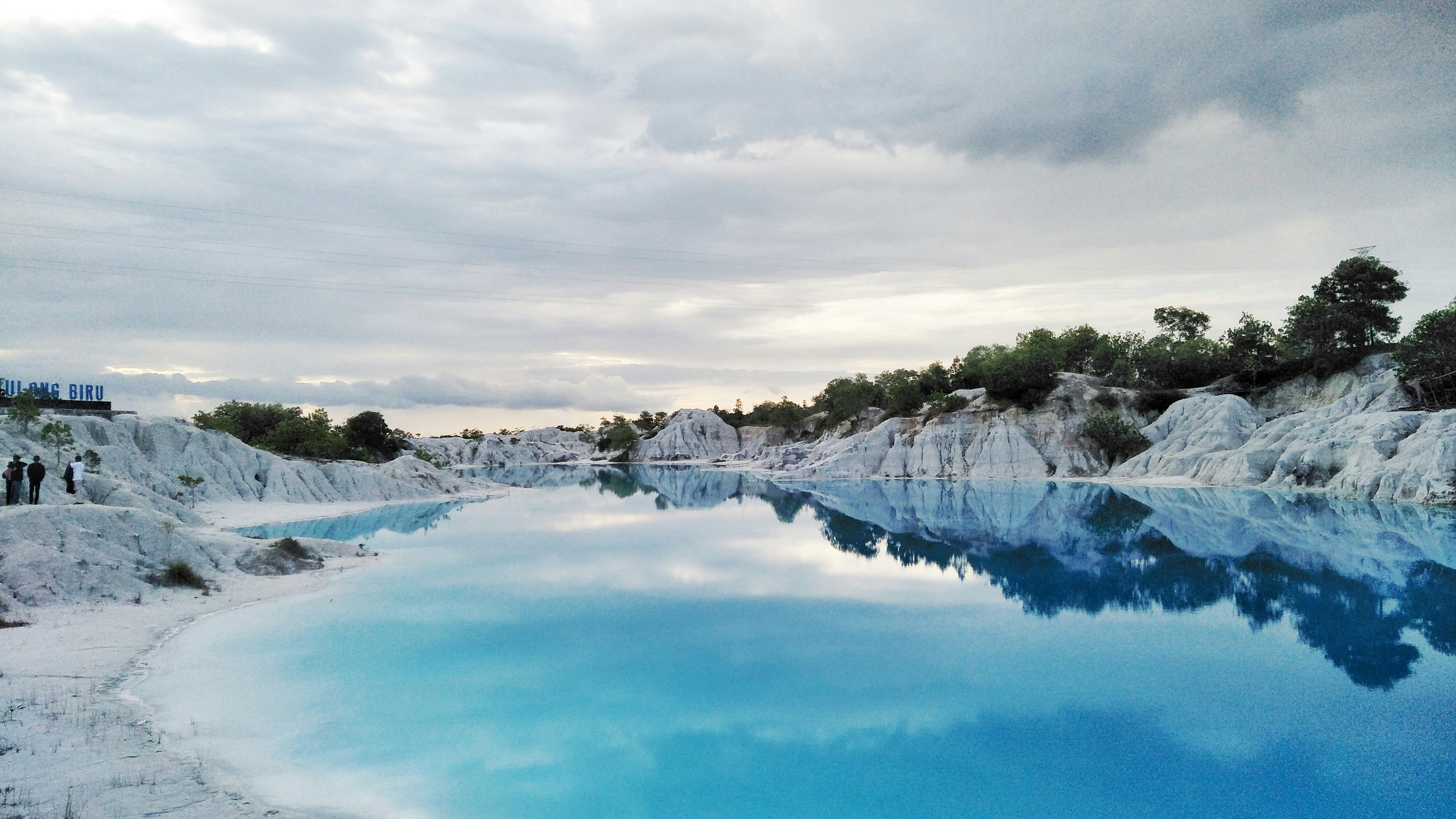 Una piscina azul rodeada de rocas blancas y árboles