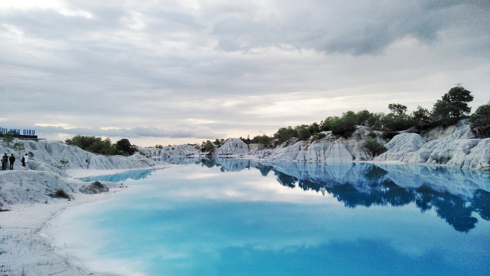 a blue pool surrounded by white rocks and trees