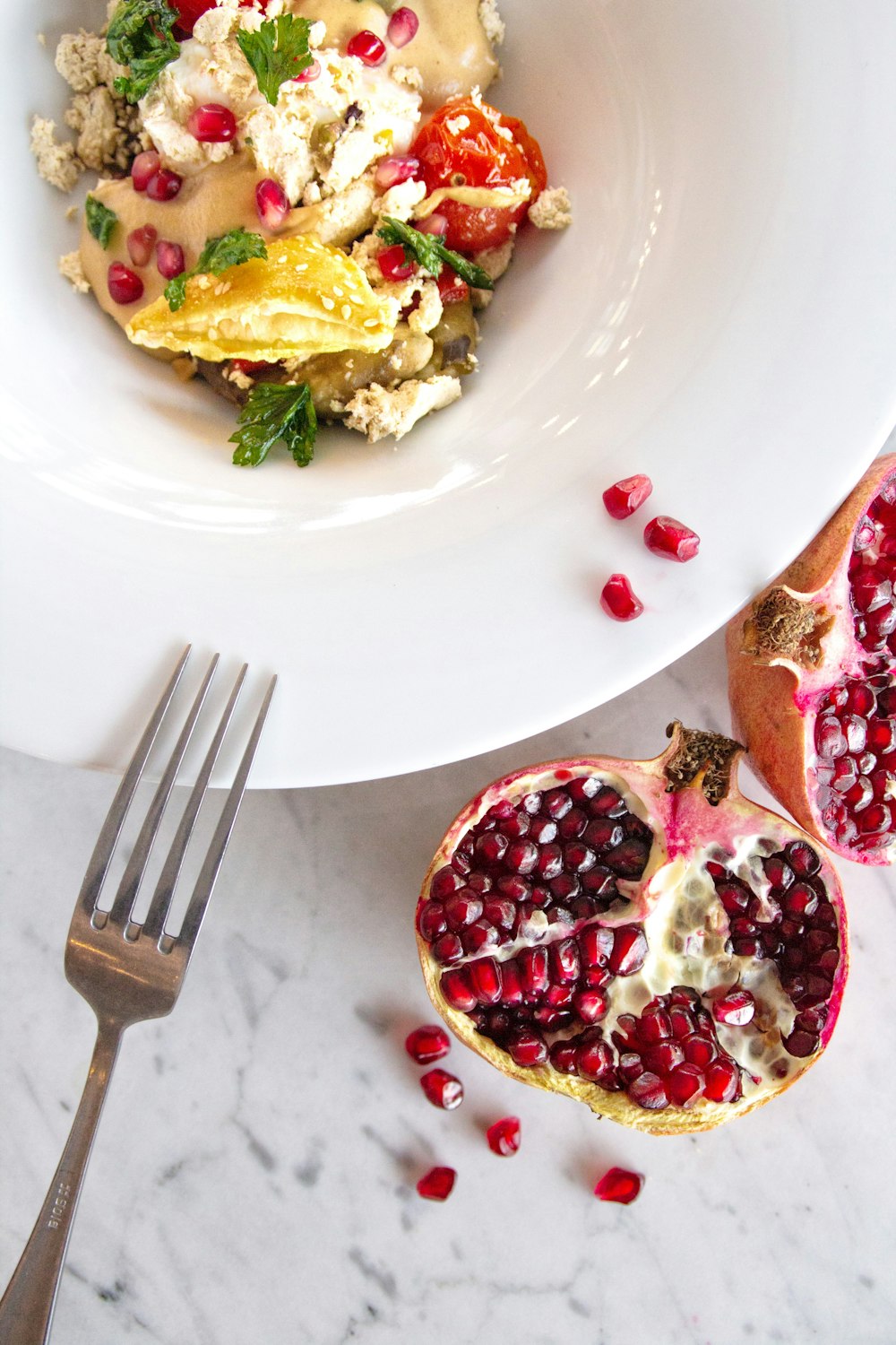 a white plate topped with a pomegranate next to a fork