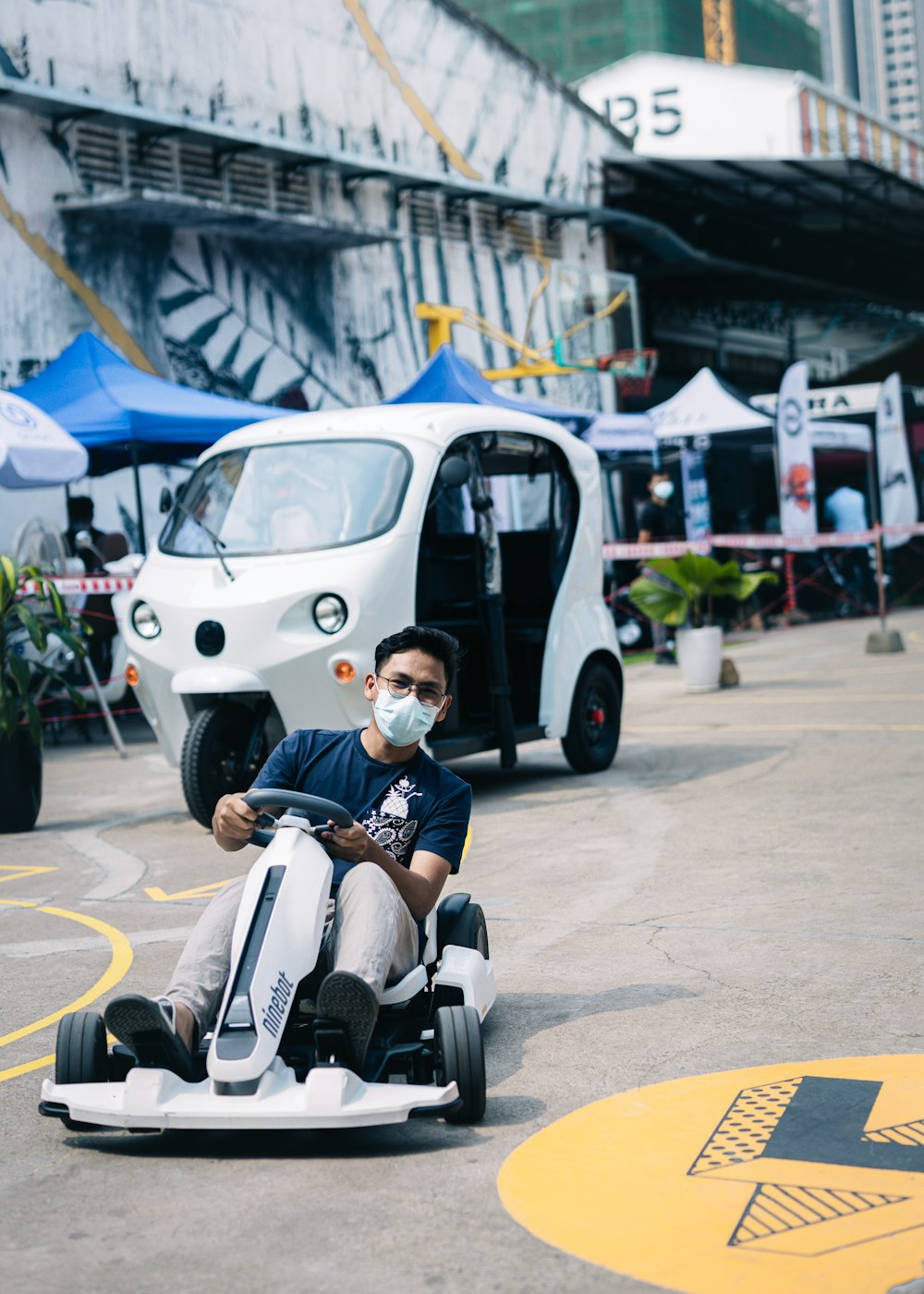 a man in a face mask rides a go - kart