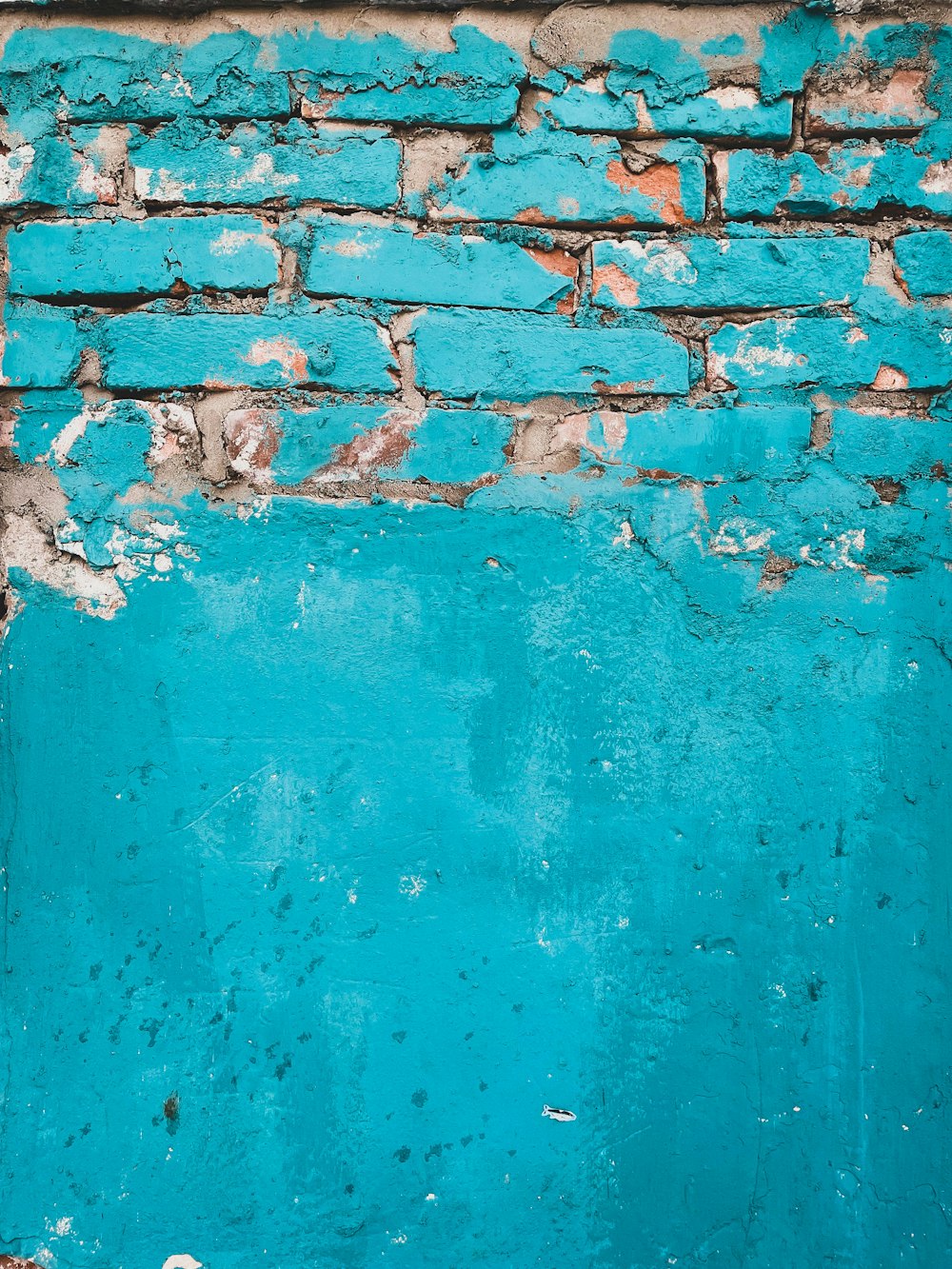 a blue brick wall with peeling paint on it