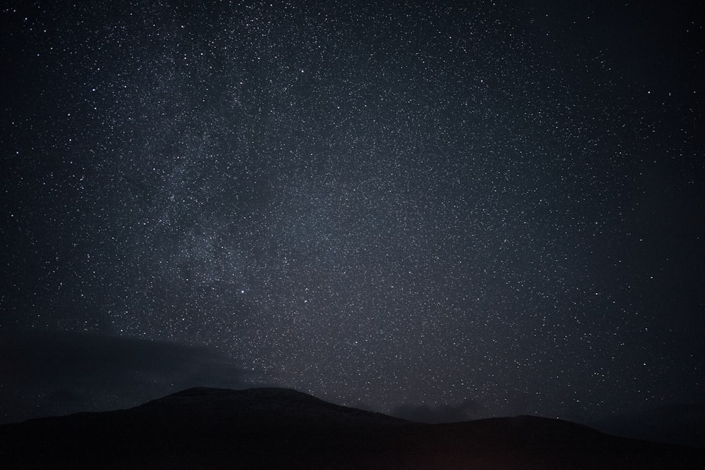 the night sky with stars above a mountain range