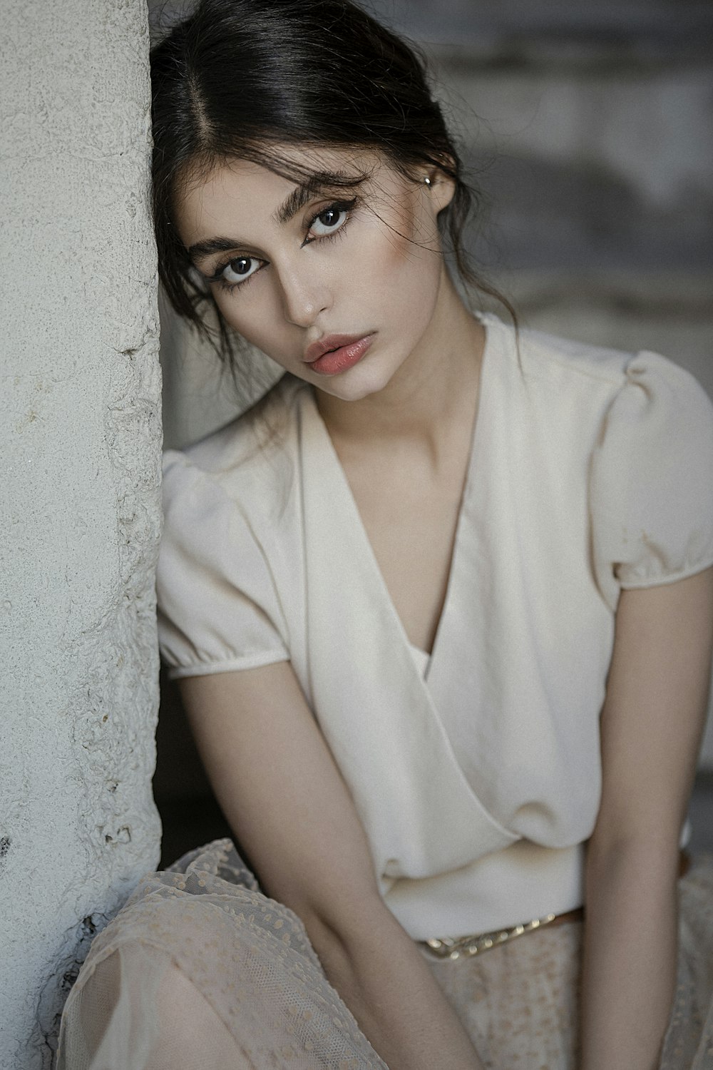 a woman sitting on the ground next to a wall