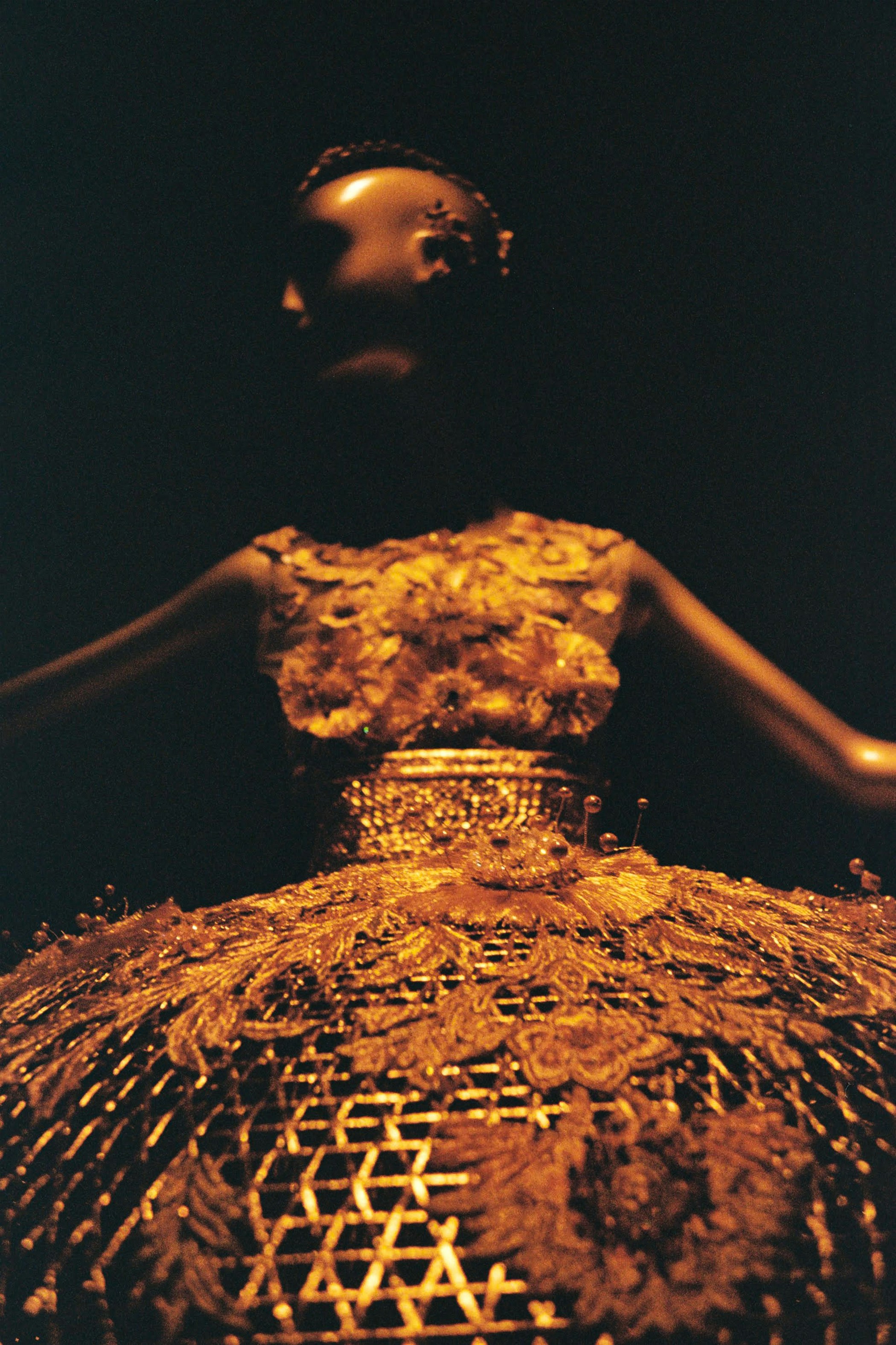 un mannequin portant une robe dorée avec un fond noir