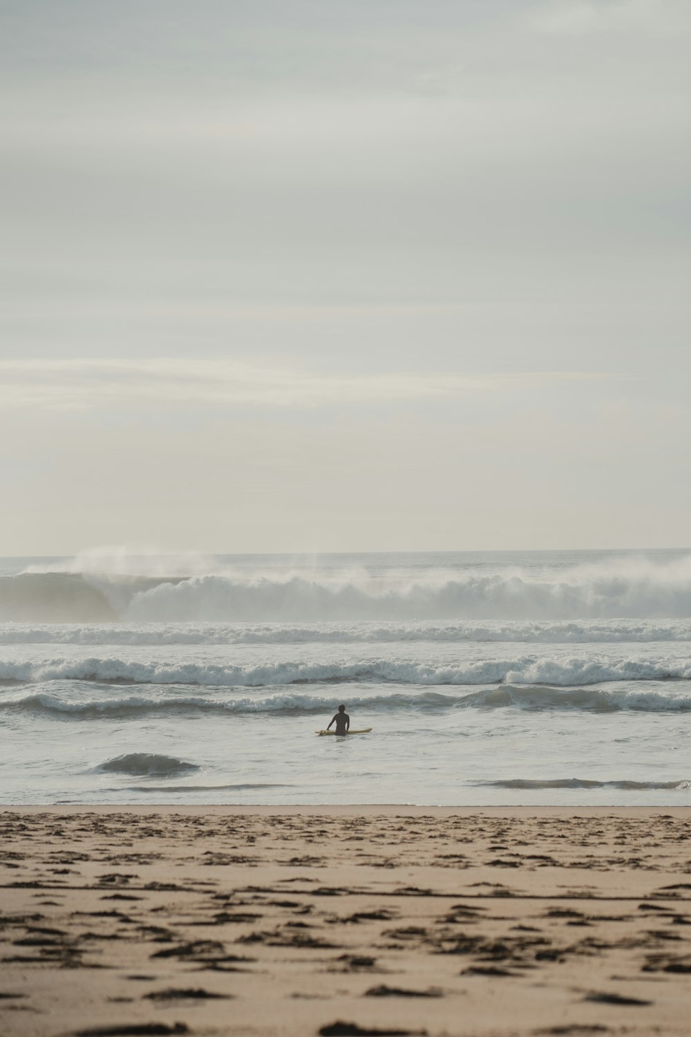 a person riding a surfboard on top of a sandy beach