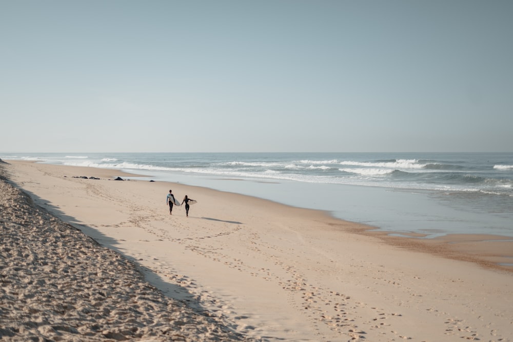 Un couple de personnes marchant le long d’une plage de sable