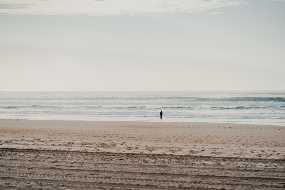 a person standing on a beach next to the ocean