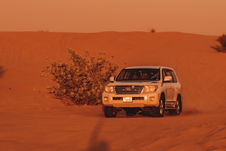 A cozy private 4x4 vehicle winding through the golden dunes of the Sahara at sunset.