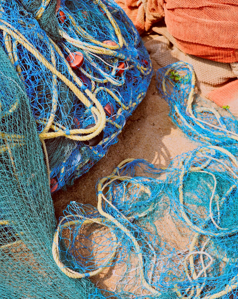 a pile of blue fishing nets sitting on top of a sandy beach