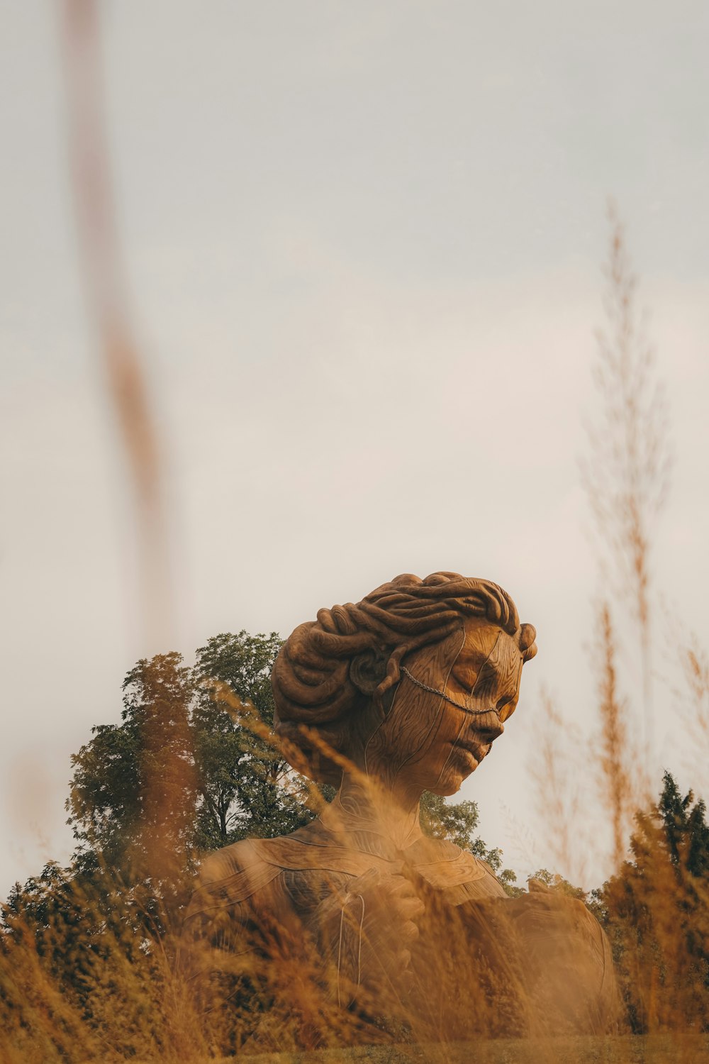 a statue of a woman in a field of tall grass