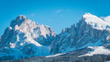 Snow-capped peaks of the Swiss Alps under a clear blue sky, viewed from a mountain trail.