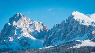 Snow-capped peaks of the Swiss Alps under a clear blue sky, viewed from a mountain trail.