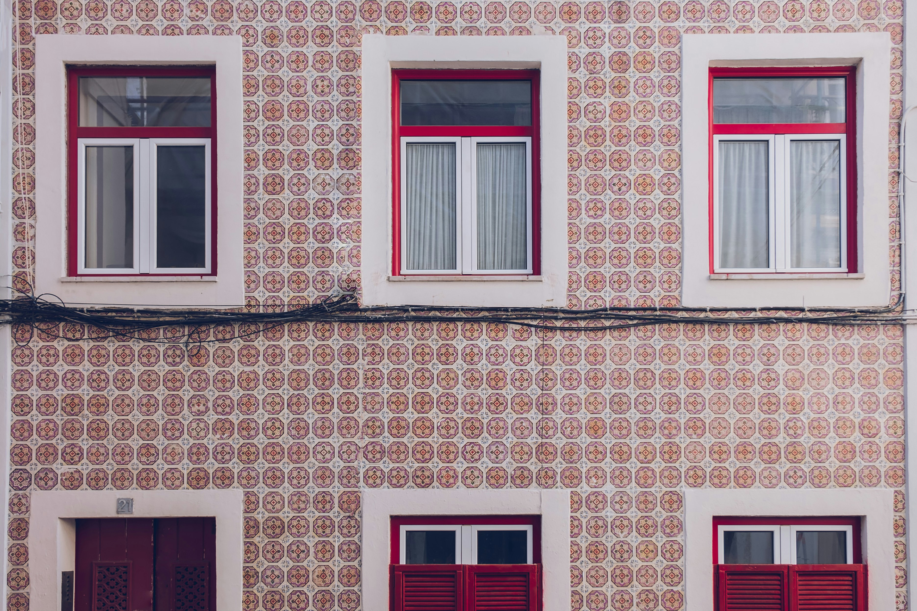 a tall building with red shutters and windows, Património Azulejar da Freguesia de Estrela