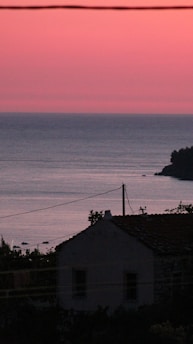 A cozy seaside cottage with a welcoming front porch overlooking the ocean at sunset.