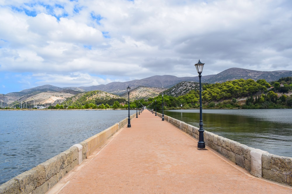 a walkway leading to a lake with mountains in the background