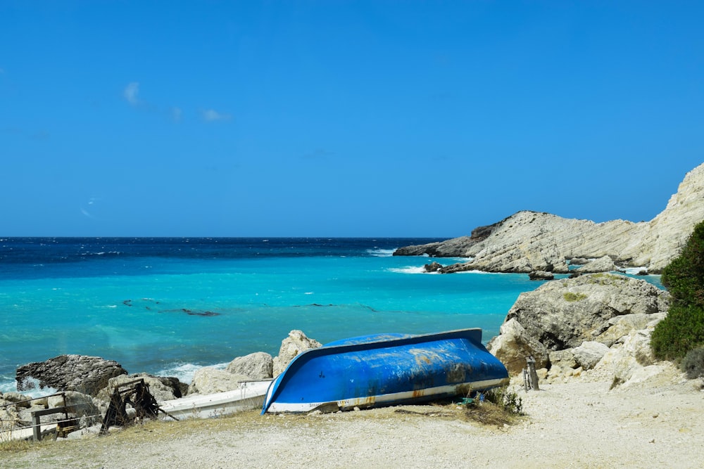 a blue boat sitting on top of a sandy beach