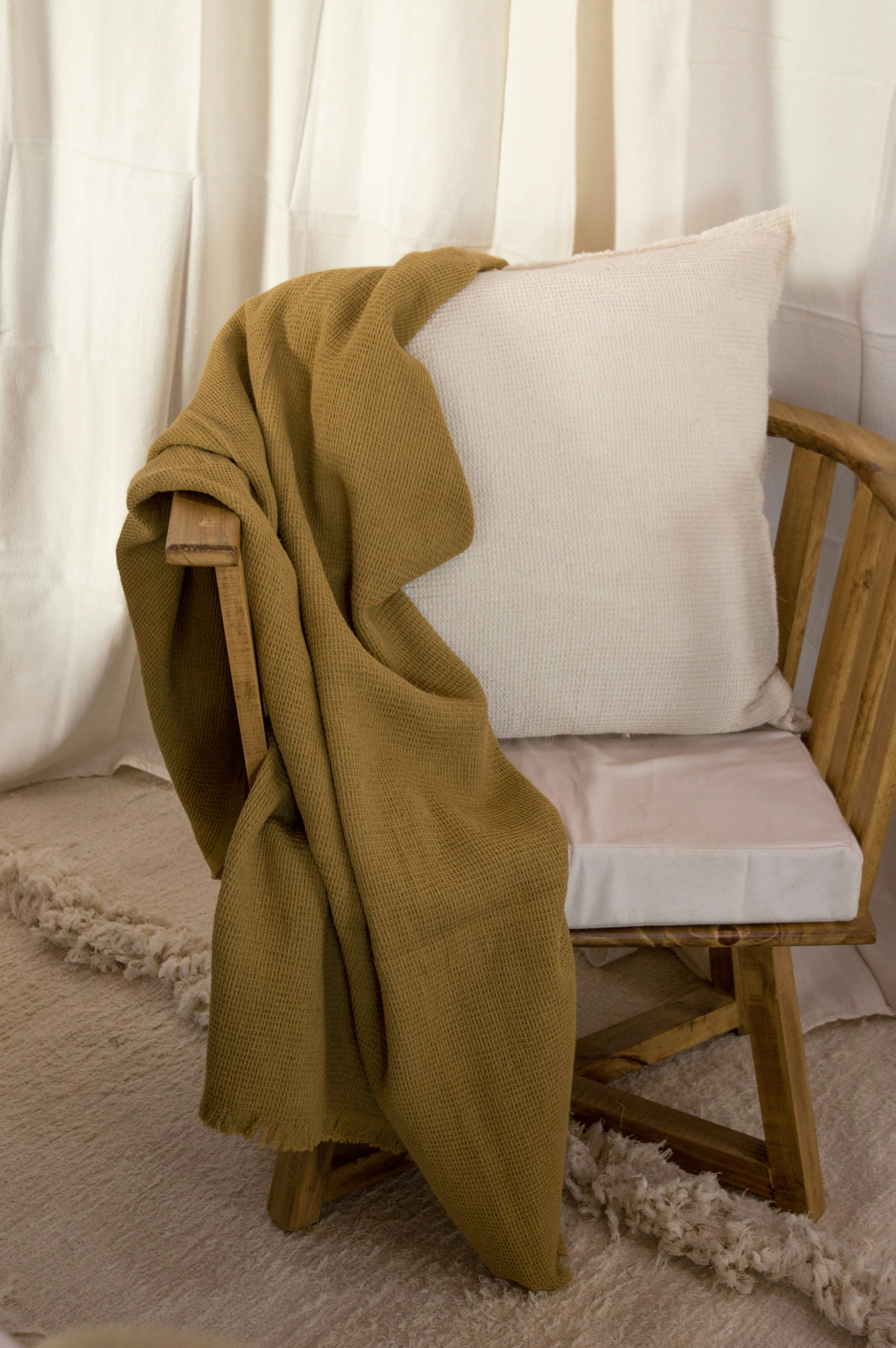Handwoven wool throw blanket in earth tones draped over white chair