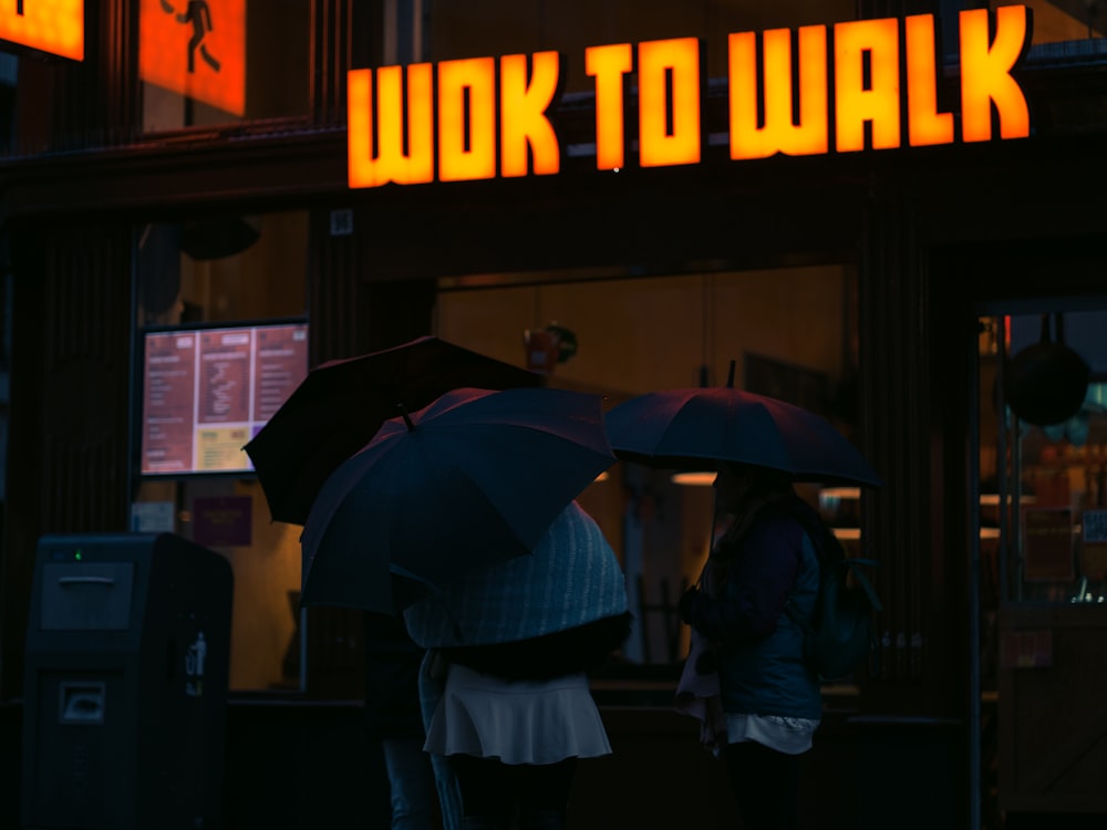 a couple of people standing under umbrellas in front of a building