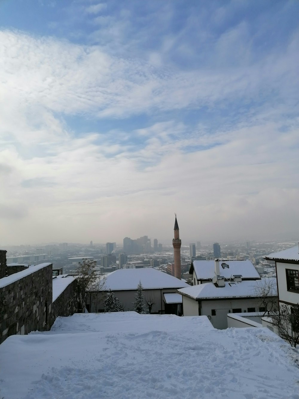 a snow covered rooftop with a view of a city in the distance