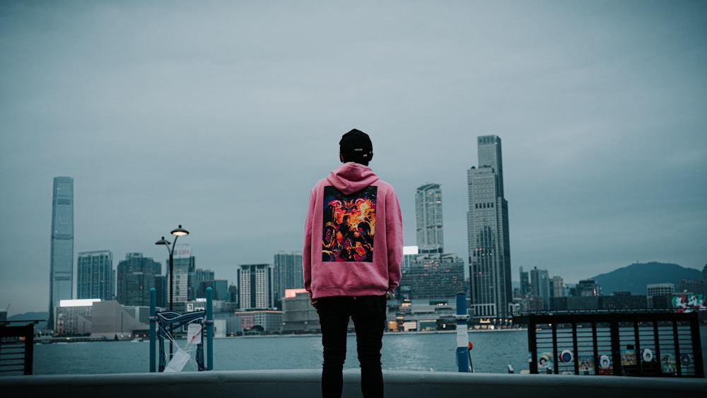 a person in a pink hoodie looking out over a body of water